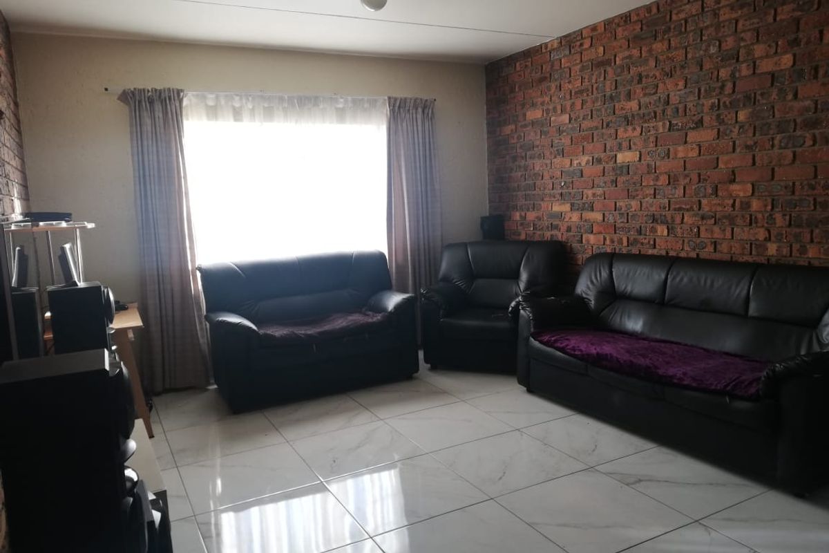 A living room featuring a prominent exposed brick feature wall and modern white porcelain floor tiles, providing a neutral base for interior design.
