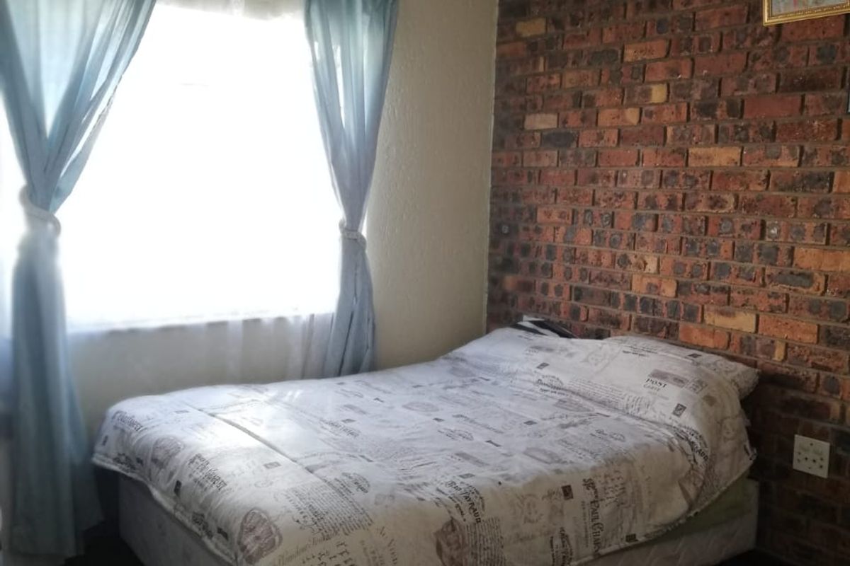 A bedroom featuring a rustic exposed brick feature wall and a window with natural light.