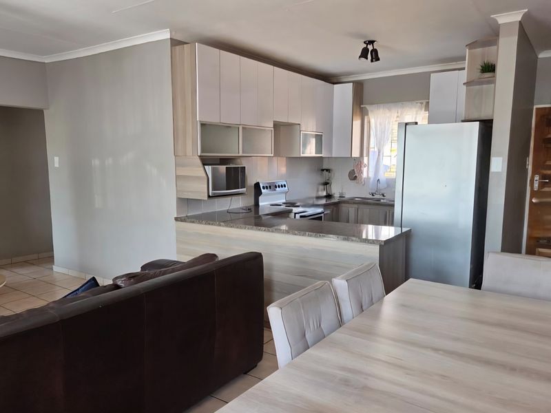 Open-plan living area featuring a modern kitchen with granite countertops, built-in cabinetry, and integrated appliances, seamlessly flowing into the dining and lounge space.