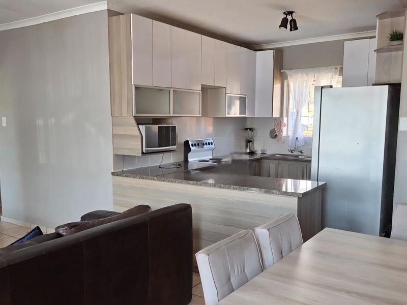 Open-plan kitchen featuring modern cabinetry, granite countertops, and a breakfast bar, seamlessly flowing into the dining and living areas.