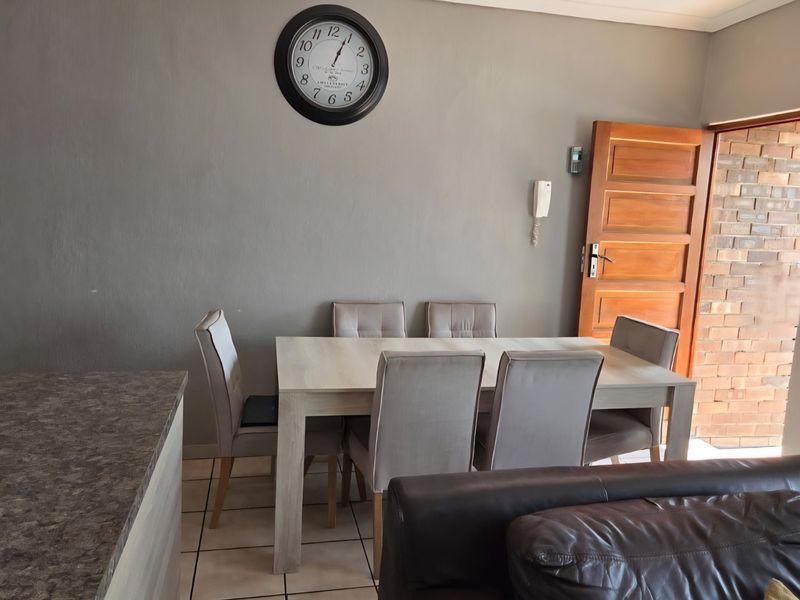 Open-plan living and dining area featuring tiled flooring, a stone-look countertop, and direct access to an exterior brick-walled entrance.