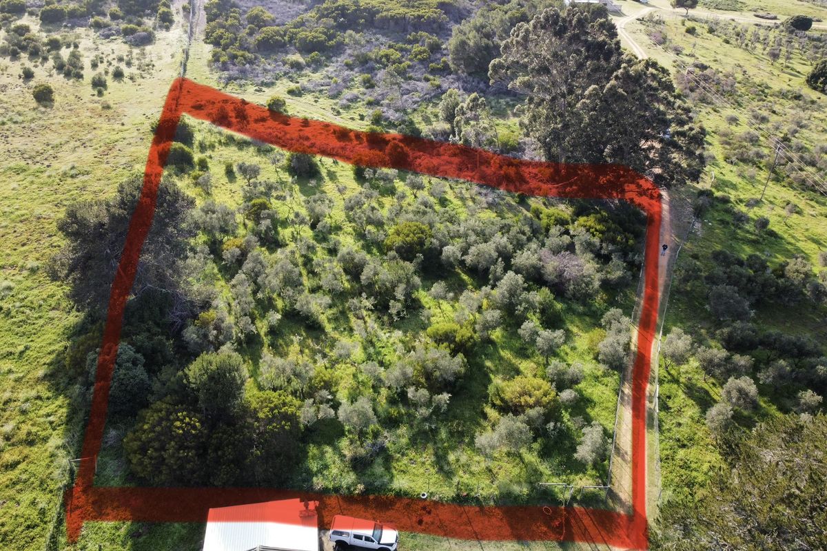 An aerial view of a vacant residential plot featuring natural vegetation and perimeter fencing, suitable for development.
