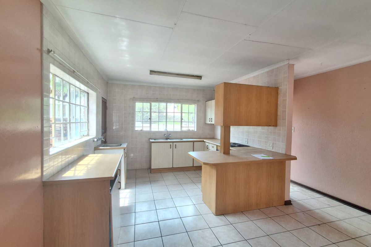 A dated kitchen featuring built-in wooden cabinetry, tiled flooring, and a breakfast bar, offering a functional layout ready for modernization.