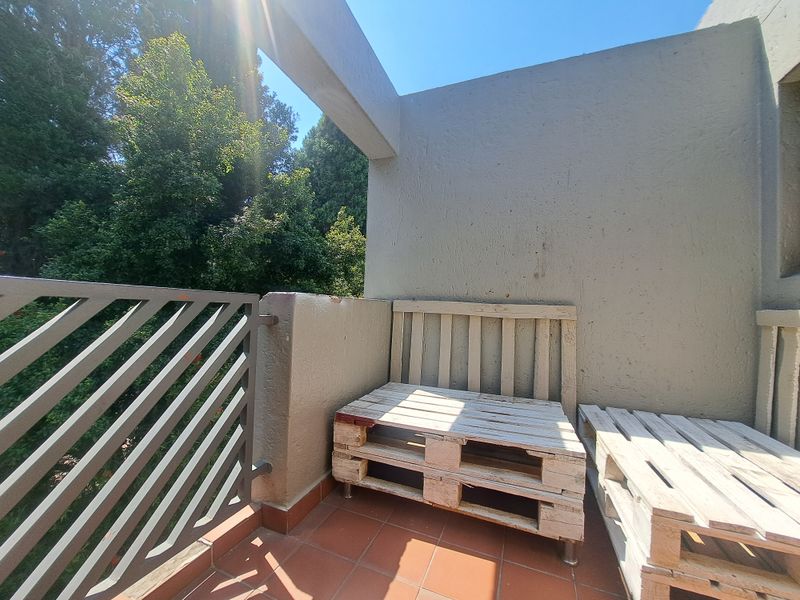 A private balcony featuring tiled flooring and a metal balustrade, offering an outdoor space with views of surrounding greenery.