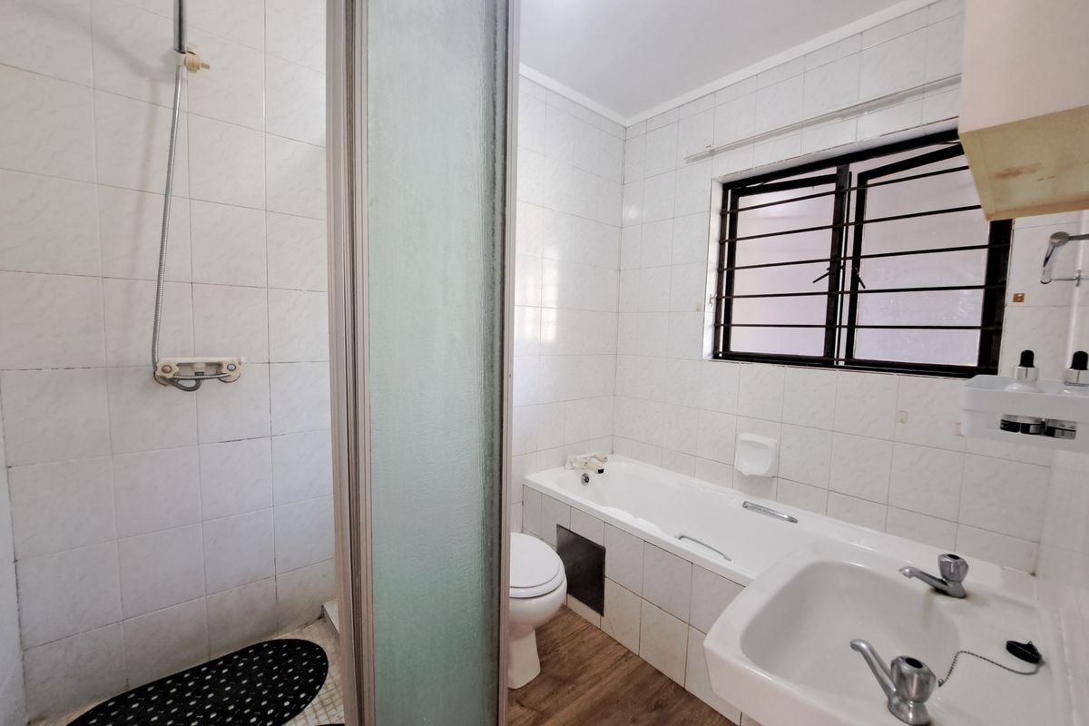 A functional bathroom featuring a separate shower, bathtub, pedestal basin, and tiled finishes, offering a clean space ready for potential modern updates.