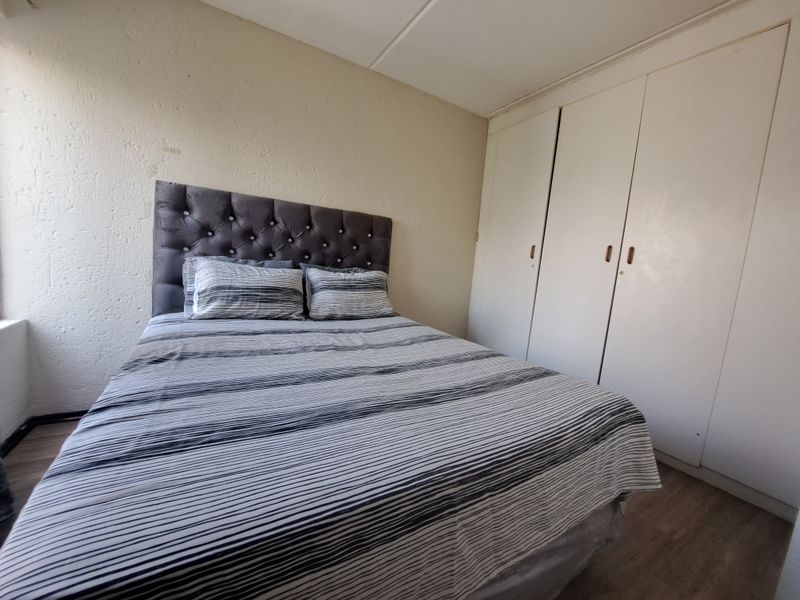 A functional bedroom featuring built-in cupboards and laminate flooring, offering a neutral base for potential interior updates.