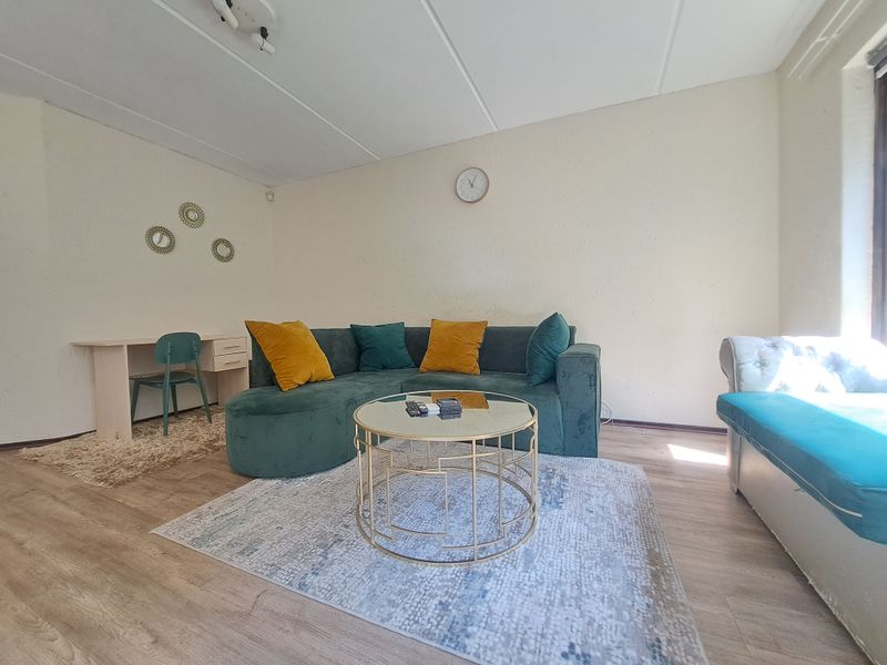 A living room featuring light-toned laminate flooring and textured walls, providing a neutral base for interior design.