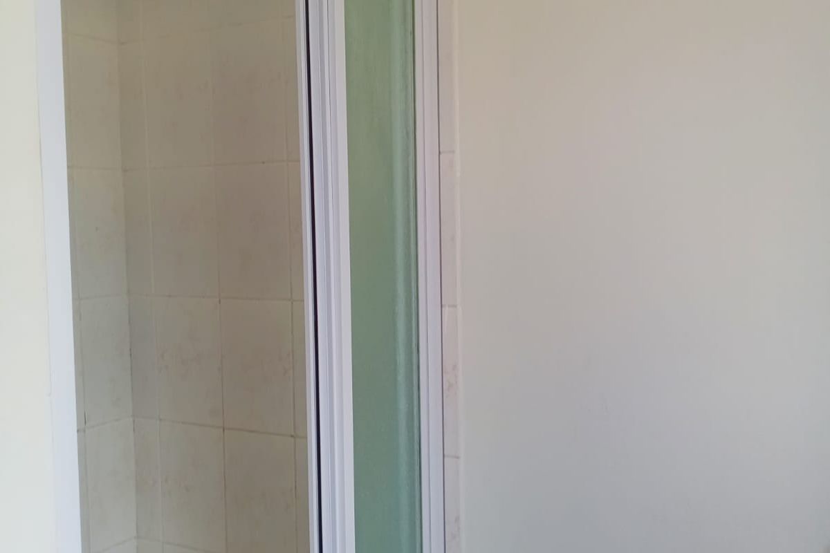 A functional shower stall featuring tiled walls and a white-framed glass door, situated within a bathroom space.