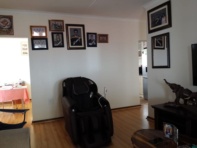 A view of the living area featuring laminate flooring and coved ceilings, with an open transition to the adjacent dining space and kitchen.