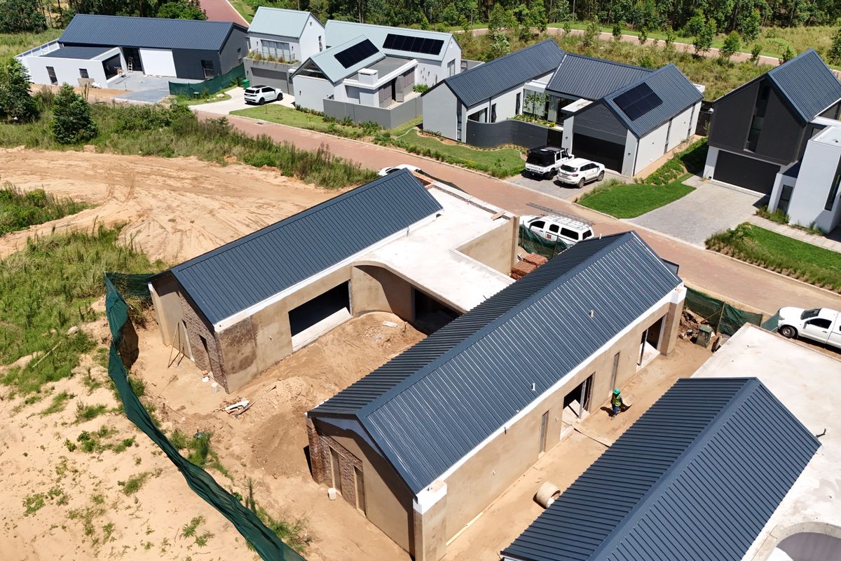 Aerial view of a residential property under construction, featuring modern metal roofing and ongoing site development within a suburban estate.