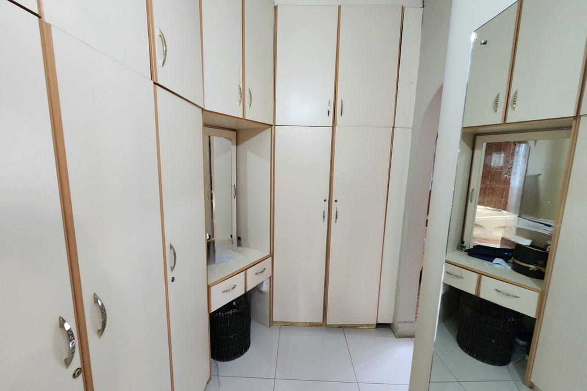 A bedroom featuring extensive built-in cabinetry with a central vanity station and tiled flooring, offering ample storage space.