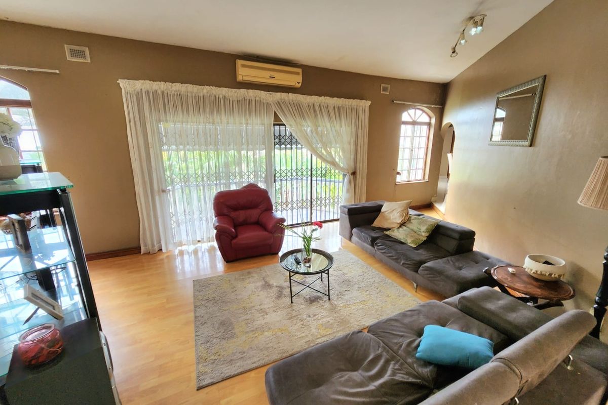 Spacious living room featuring laminate flooring, a split-system air conditioner, and large sliding glass doors leading to the exterior.