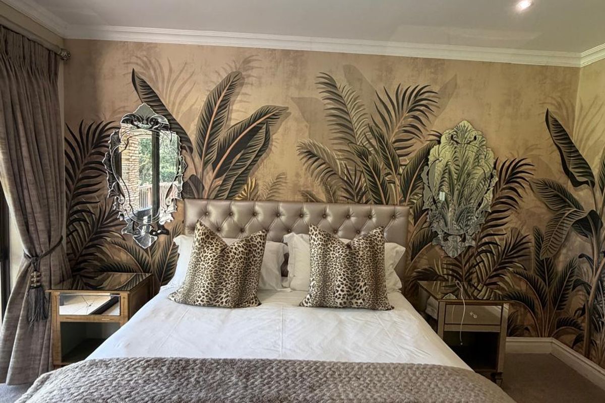 A well-maintained bedroom featuring recessed downlighting, crown molding, and a decorative feature wall with botanical wallpaper.