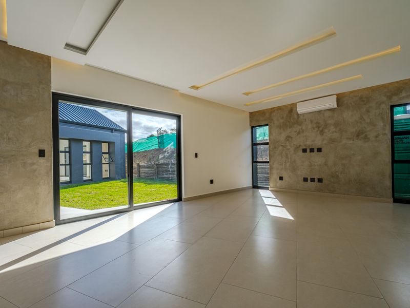 Spacious, modern living area featuring tiled floors, recessed ceiling lighting, a split-system air conditioner, and large sliding glass doors opening to the rear garden.