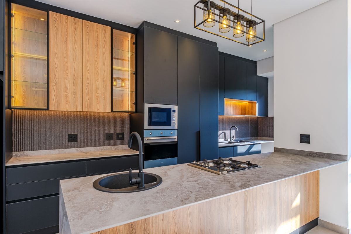Modern kitchen featuring high-end cabinetry, stone countertops, built-in appliances, gas hob, and stylish pendant lighting in a contemporary open-plan layout.