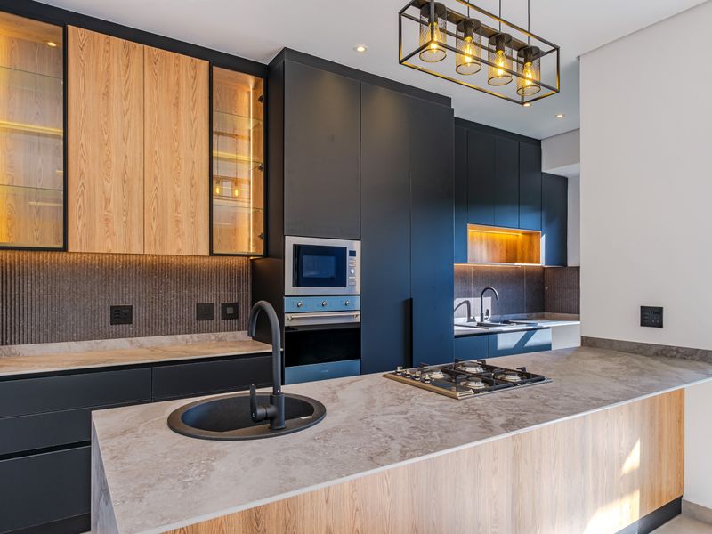 Modern kitchen featuring high-end cabinetry, stone countertops, built-in appliances, gas hob, and stylish pendant lighting in a contemporary open-plan layout.