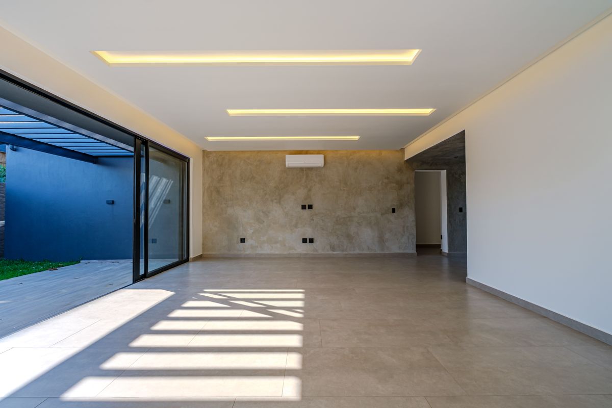 Spacious, modern living area featuring recessed ceiling lighting, a textured feature wall, split-system air conditioning, and large sliding doors opening to an outdoor patio.