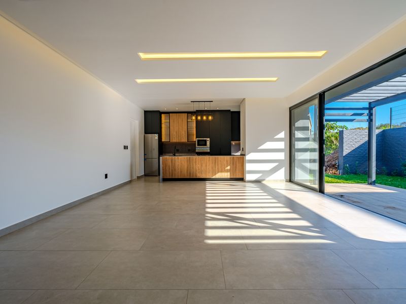 Spacious open-plan living and kitchen area featuring modern cabinetry, recessed lighting, and large sliding doors opening onto an outdoor patio.