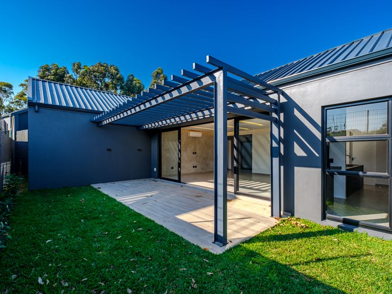 Modern rear patio featuring a sleek metal pergola, tiled flooring, and large sliding glass doors providing seamless indoor-outdoor flow.