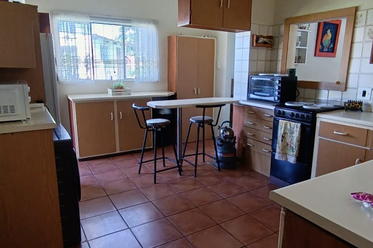 A functional kitchen featuring wood-finish cabinetry, tiled splashbacks, and a breakfast bar area with tiled flooring.