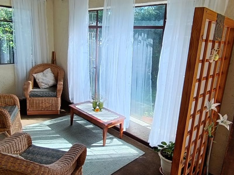 A sunlit living area featuring large glass sliding doors, textured walls, and direct access to the garden.