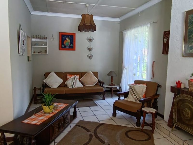 A cozy living room featuring a brick fireplace, tiled flooring, and a ceiling-mounted light fixture.