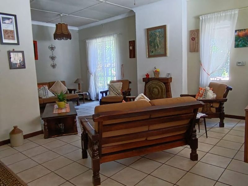 A spacious living room featuring neutral wall tones, tiled flooring, and large windows that provide natural light throughout the area.