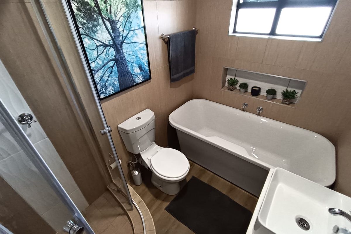 A modern bathroom featuring a freestanding bathtub, a separate glass-enclosed shower, a wall-mounted basin, and a built-in wall niche for storage.