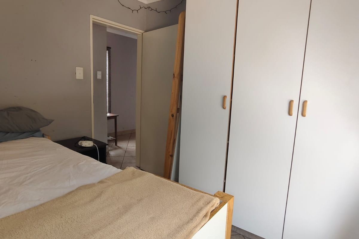 A bedroom featuring built-in white cabinetry, tiled flooring, and a doorway leading to an adjacent room.