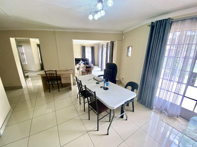 Spacious open-plan living and dining area featuring neutral tiled flooring, ample natural light, and direct access to the outdoor space through sliding glass doors.