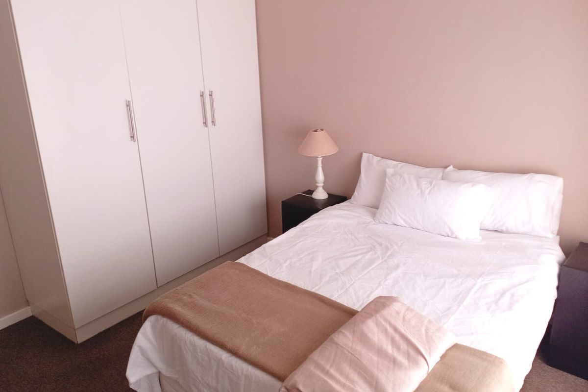A bedroom featuring a built-in wardrobe with white cabinetry and neutral wall tones.