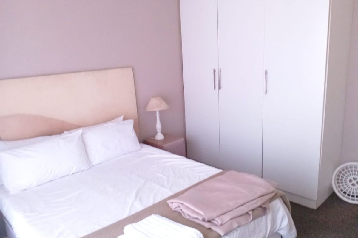 A bedroom featuring a neutral color palette and a large white built-in wardrobe providing ample storage space.