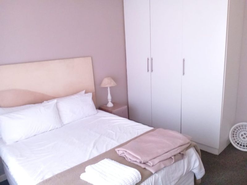 A bedroom featuring a neutral color palette and a large white built-in wardrobe providing ample storage space.