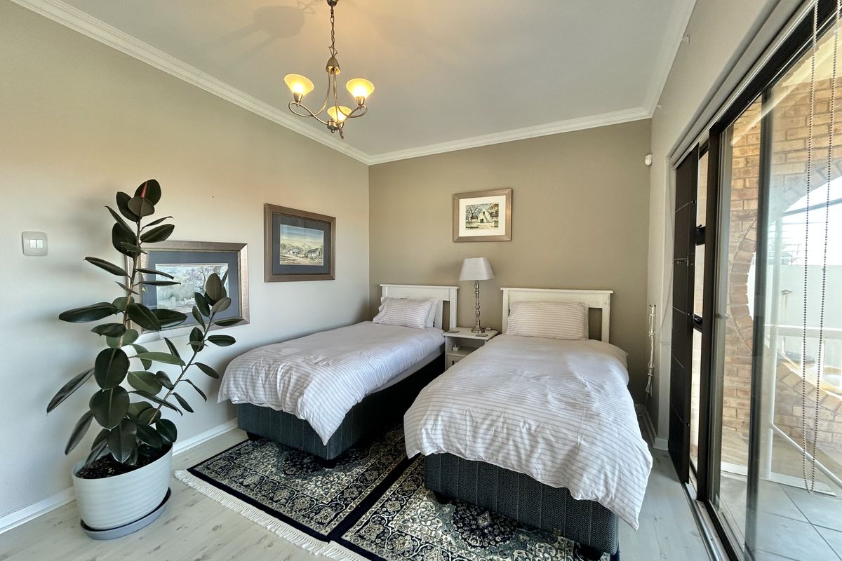 A well-maintained bedroom featuring neutral wall tones, crown molding, and large sliding glass doors providing access to an outdoor area.