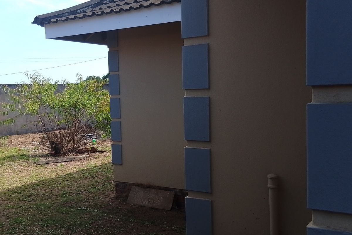 A view of the rear exterior of the house, featuring a side facade with decorative corner detailing and an adjacent garden area with boundary wall.
