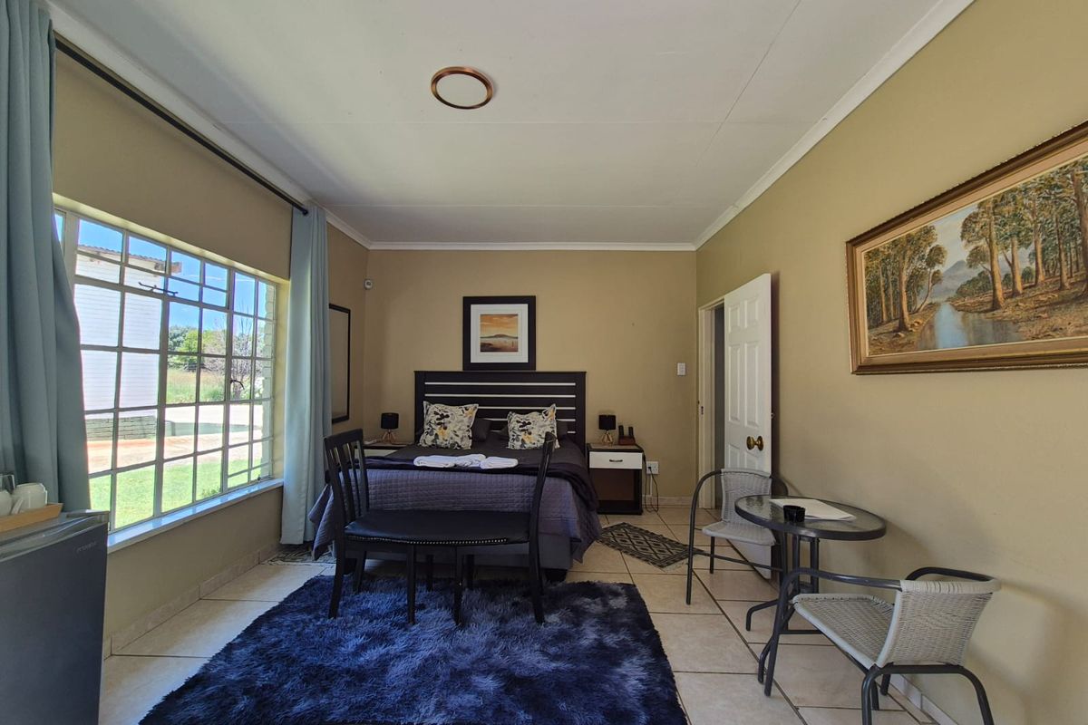 A spacious bedroom featuring large windows, tiled flooring, and a neutral color palette, providing a comfortable and well-lit living space.