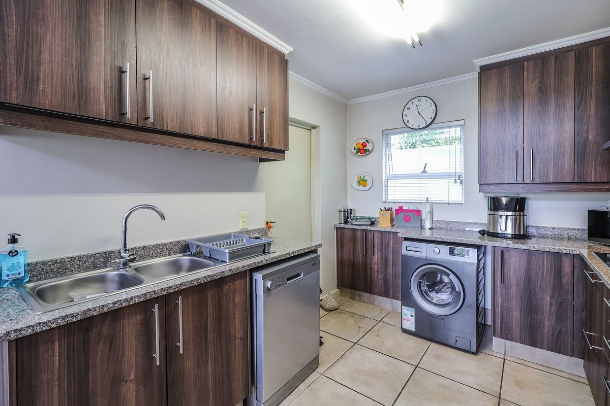 A functional kitchen featuring dark wood cabinetry, granite countertops, a double sink, and dedicated space for a dishwasher and washing machine.