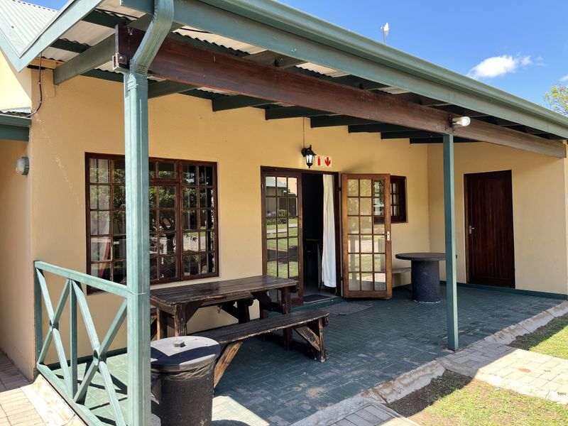 A covered outdoor patio area featuring paved flooring, timber support beams, and direct access to the interior through classic french doors.