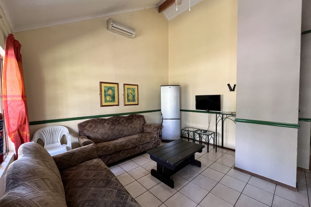 A living room featuring vaulted ceilings, ceramic tiled flooring, and a wall-mounted air conditioning unit.