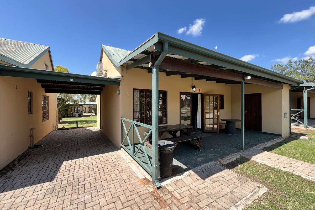 Rear view of the property featuring a covered patio area, paved driveway, and well-maintained exterior walls with timber accents.