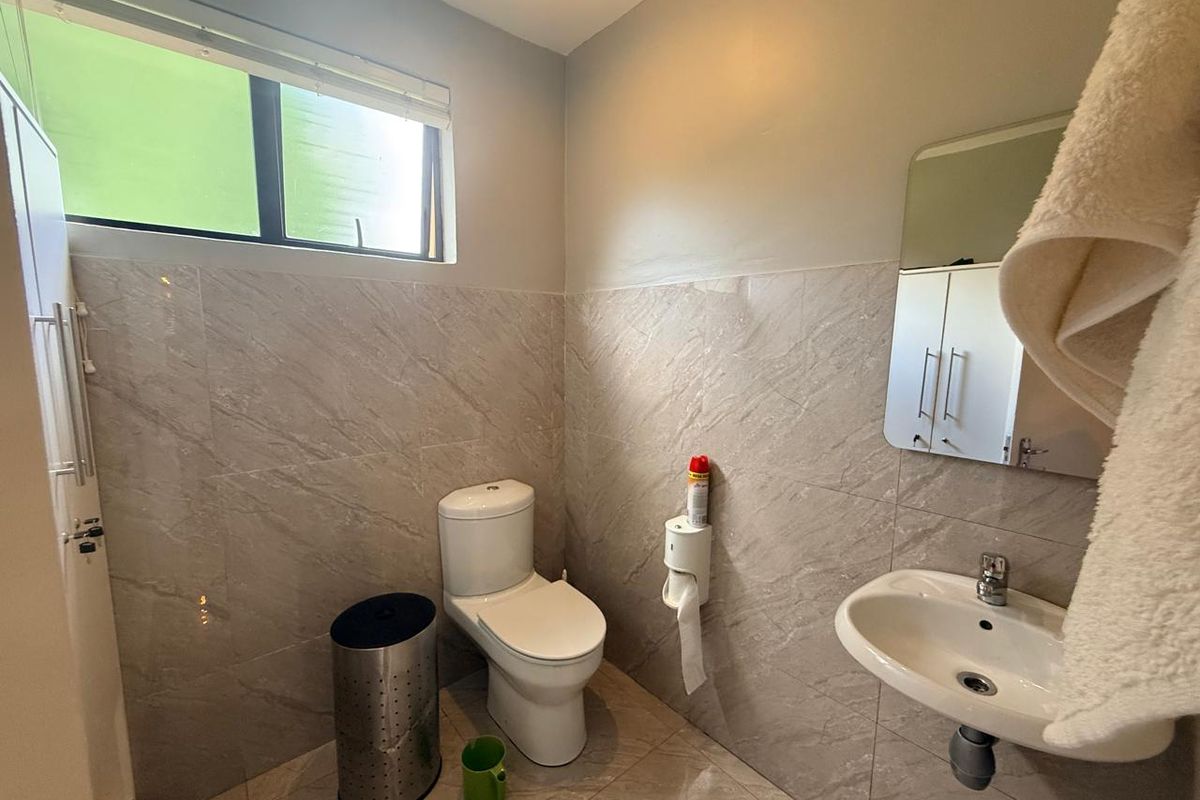 A functional bathroom featuring modern marble-look wall tiles, a wall-mounted basin, and a standard toilet.