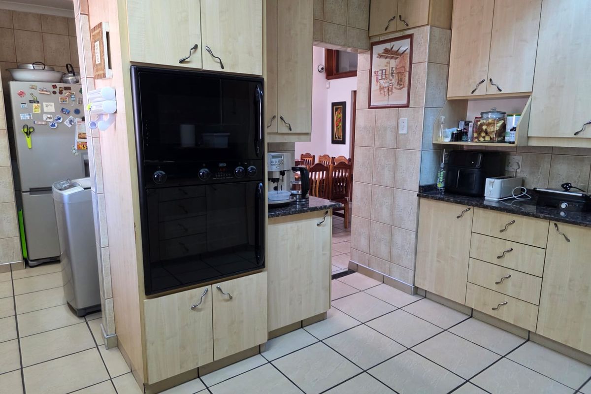 Functional kitchen featuring light wood-toned cabinetry, dark granite countertops, tiled flooring, and a built-in eye-level oven.
