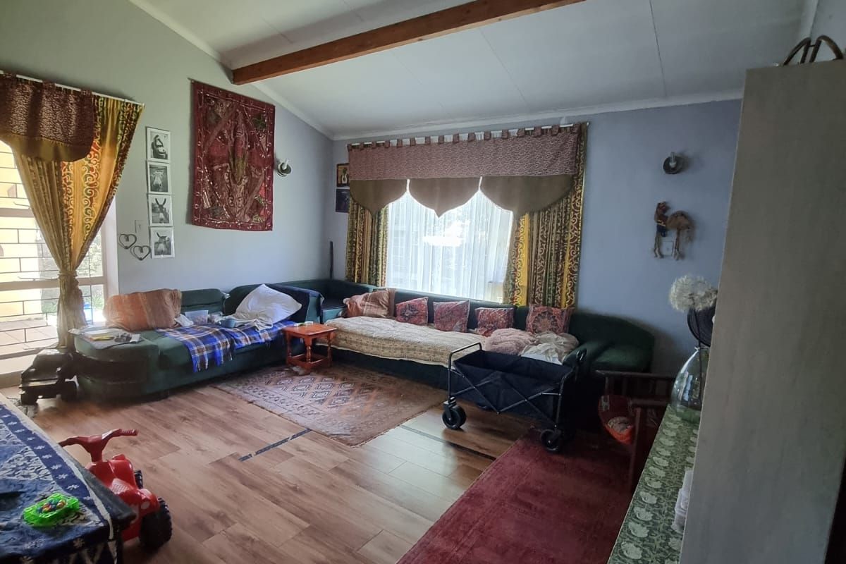 Spacious living room featuring vaulted ceilings with exposed timber beams and wood-look laminate flooring, offering a bright and open atmosphere.