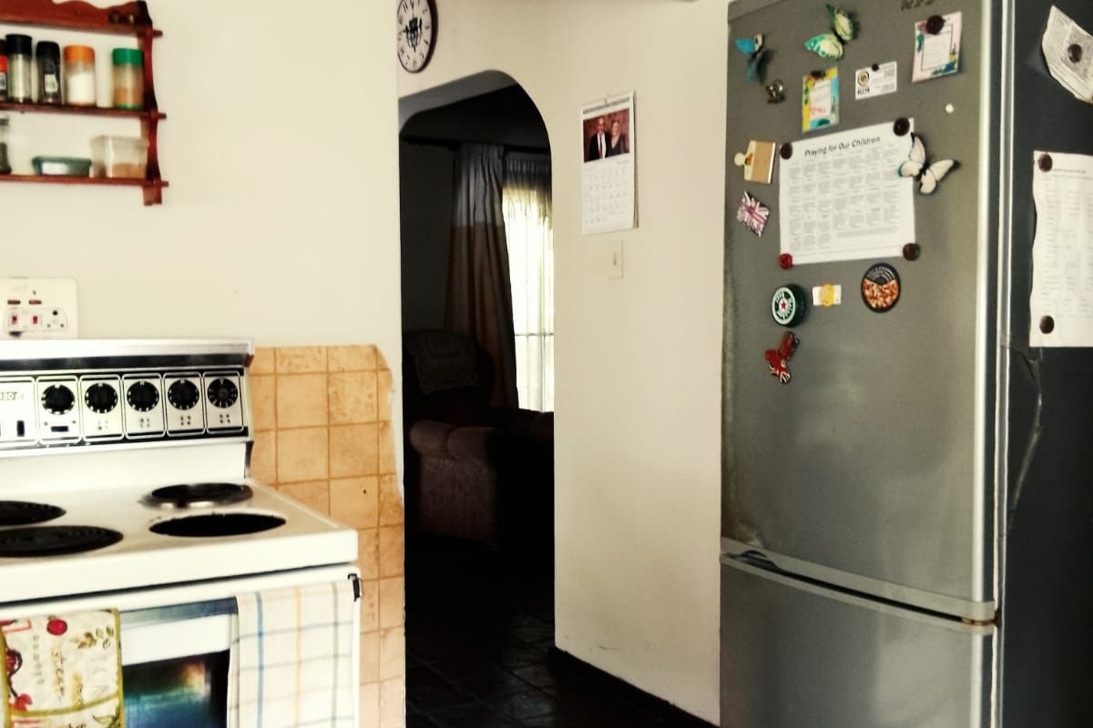 A functional kitchen area featuring a freestanding stove and tiled flooring, with an arched doorway leading to the adjacent living space.