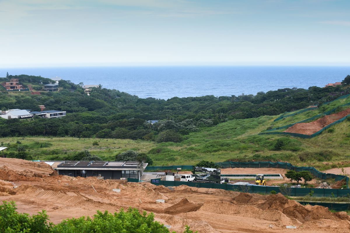 Aerial view of a coastal development site featuring a swimming pool under construction amidst natural landscape and ocean views.