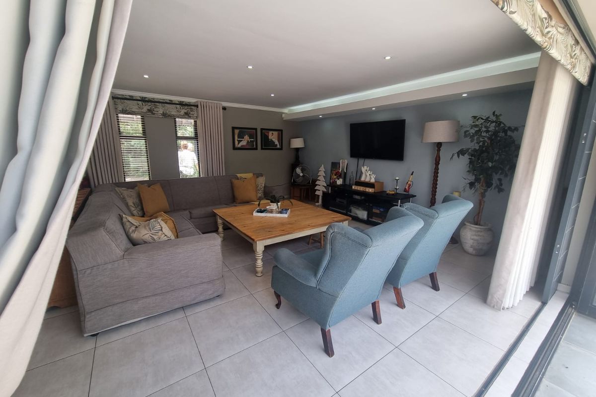 A comfortable living room featuring large format floor tiles, recessed ceiling lighting, and wide sliding doors that open to an outdoor area.