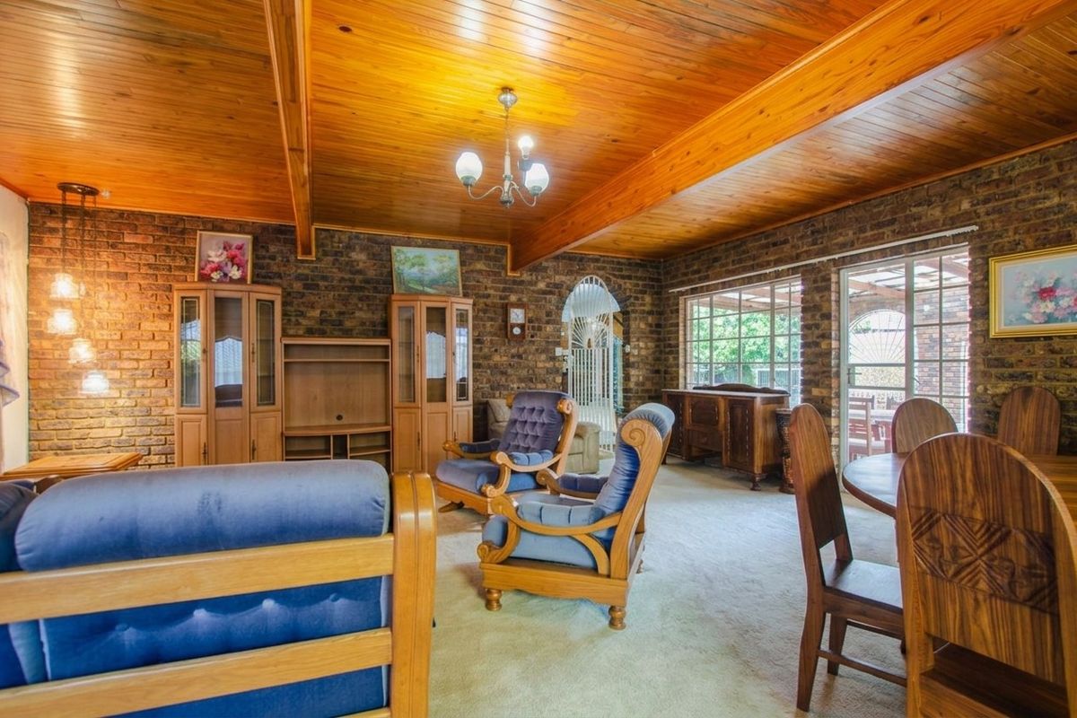 Spacious living room featuring exposed brick walls, a warm timber-paneled ceiling with exposed beams, and large sliding doors providing natural light and garden access.