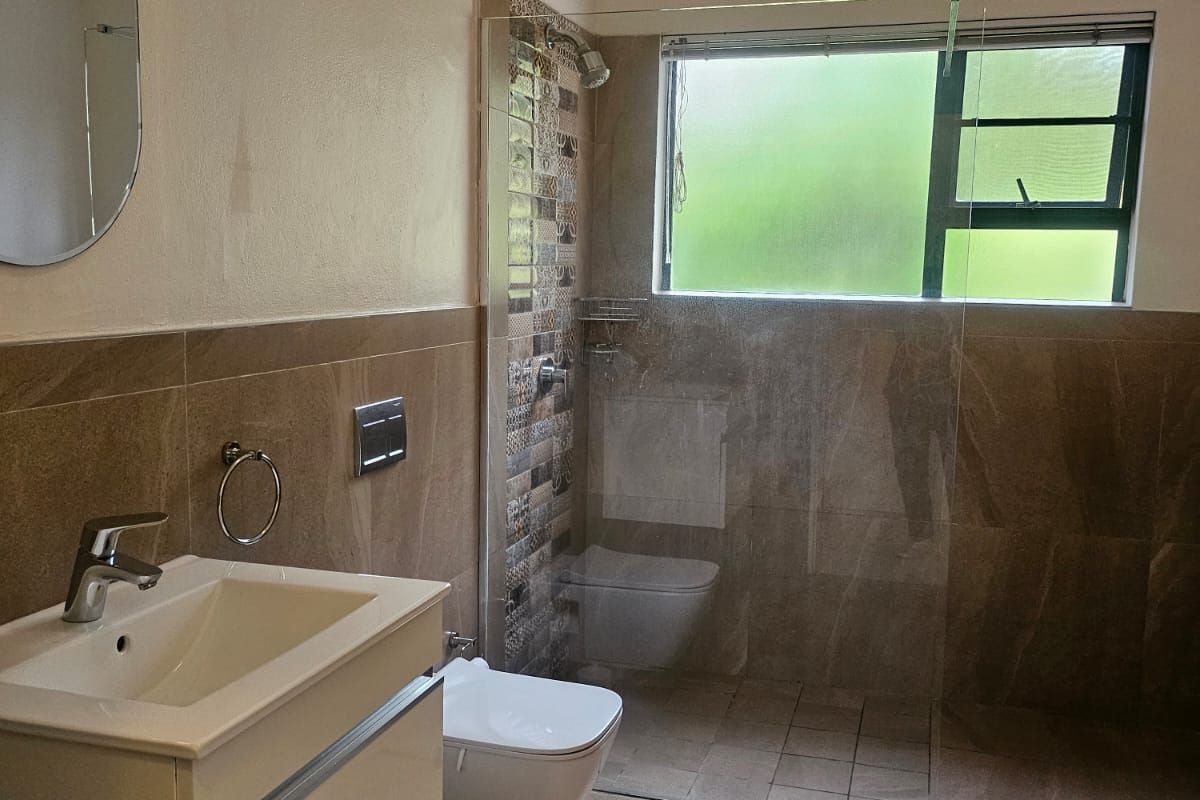 Modern bathroom featuring a wall-mounted vanity, floating toilet, and a spacious walk-in shower with glass screen and contemporary tiled finishes.