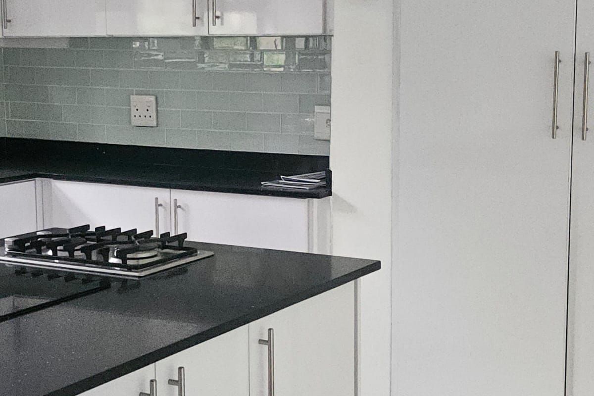 Modern kitchen featuring white cabinetry, dark stone countertops, a gas hob, and a light-toned subway tile backsplash.