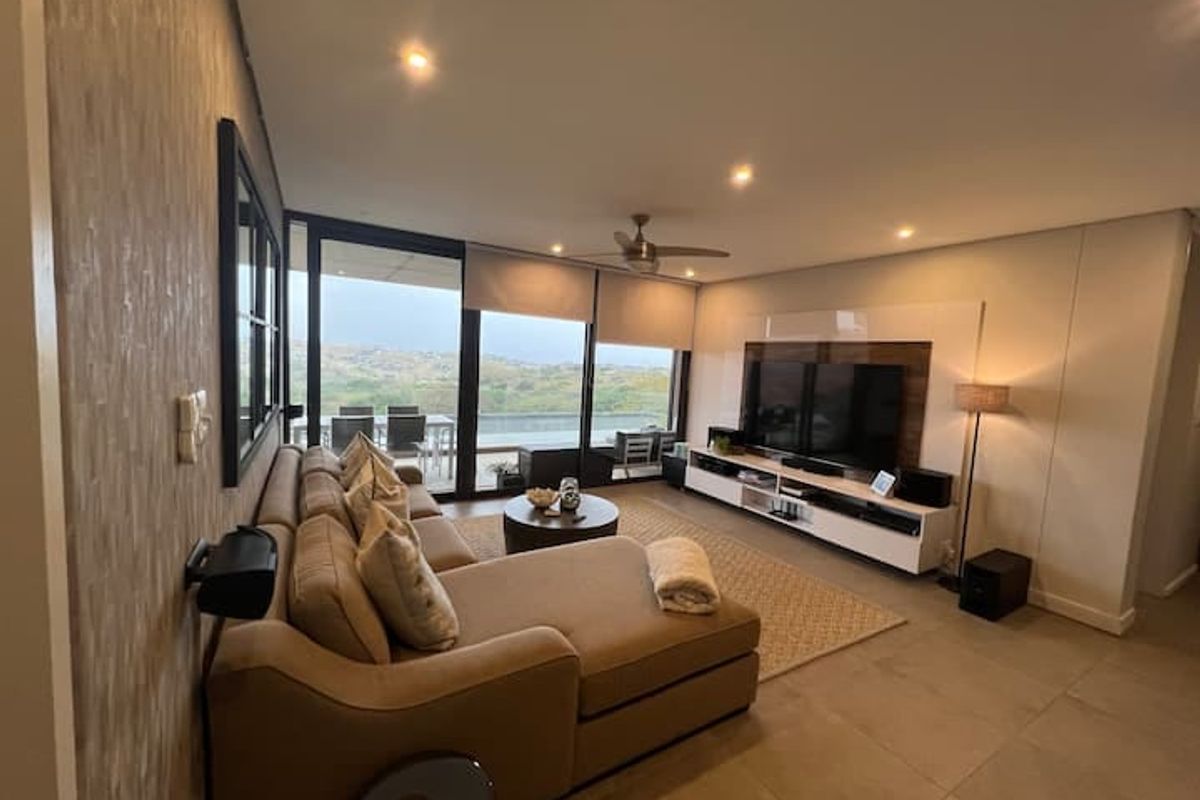Spacious living room featuring tiled floors, recessed lighting, a ceiling fan, and large sliding glass doors opening to a balcony with scenic views.